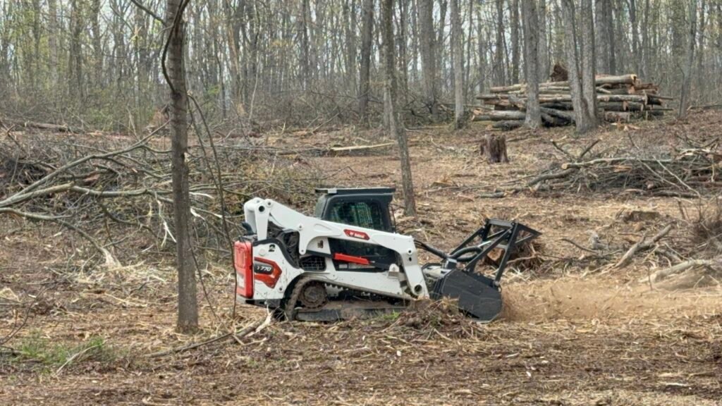 A white tractor is mulching in the forest area.